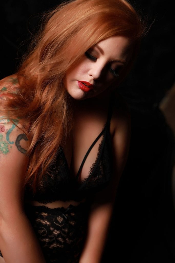 Woman with long red hair poses during boudoir session.